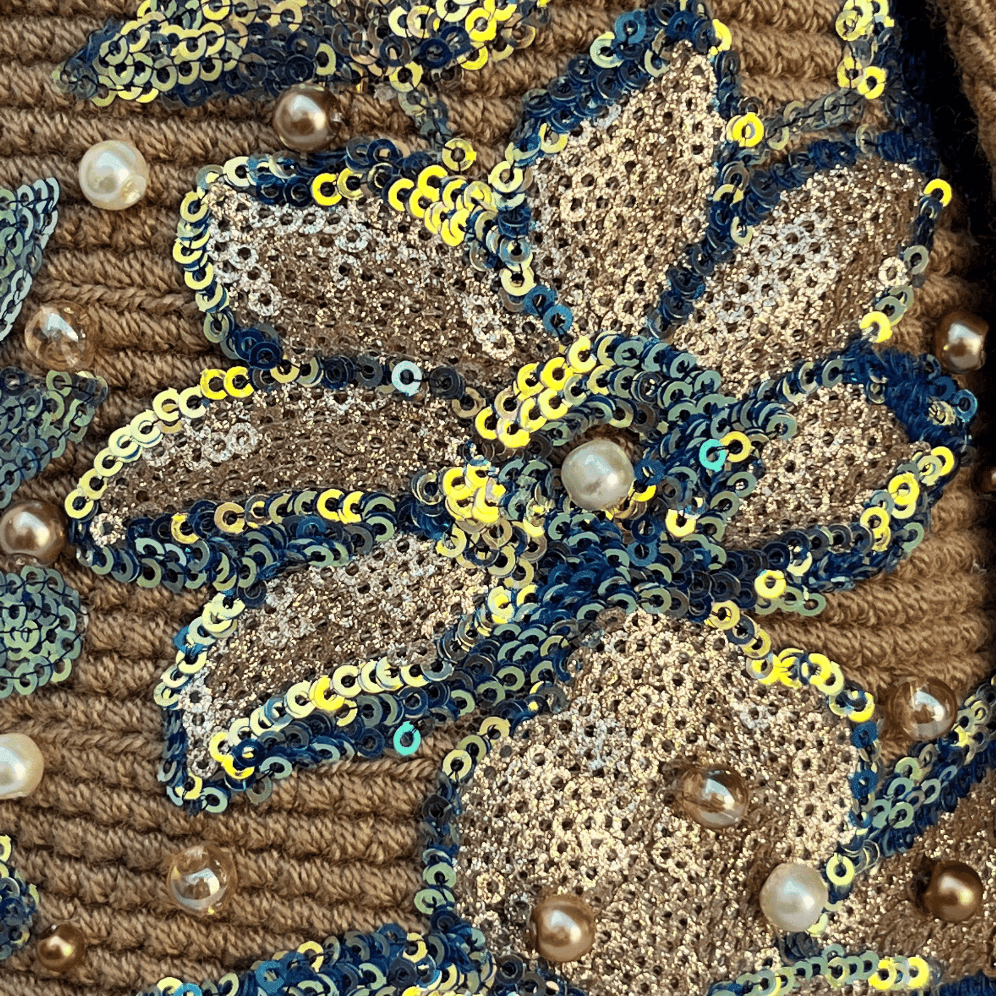 Detalle del recamado de mochila wayuu con flores de lentejuelas caqui y azul
